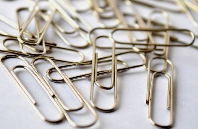 A loose scattering of steel paperclips on a pale surface.